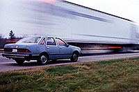 /images/133/1998-11-lancing-tempo-semi.jpg - #00169: my blue 1986 Ford Tempo … them trucks go faaast … Nov 1998 -- Lancing, Michigan