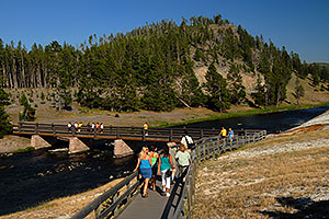 People returning from Excelsior Geyser Crater on a bridge over Firehole River